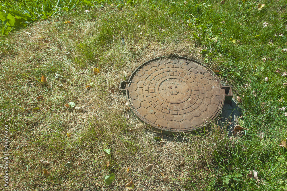Sewer hatch with a smile in the grass Sewer hatch with a smile in the grass