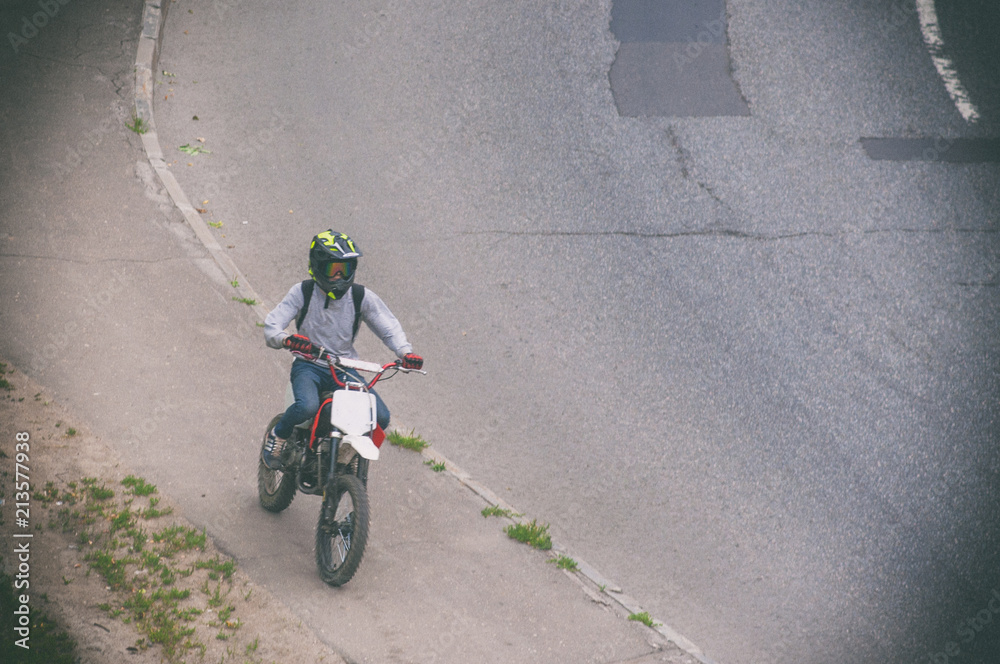 Obraz premium A young guy is riding a motorcycle on the sidewalk