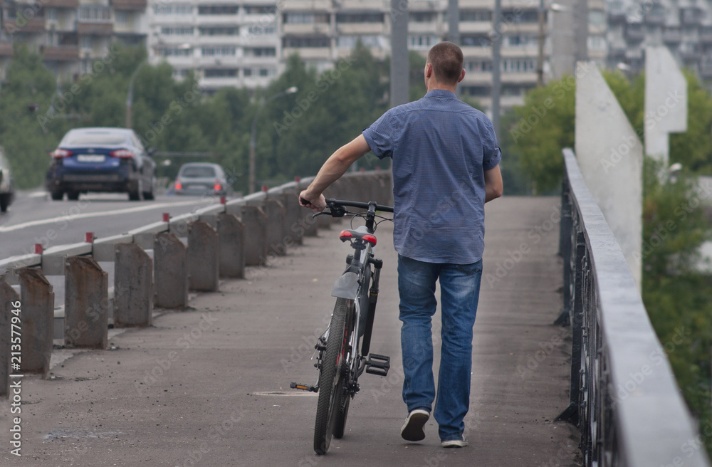 A man with a bicycle is walking along a bridge