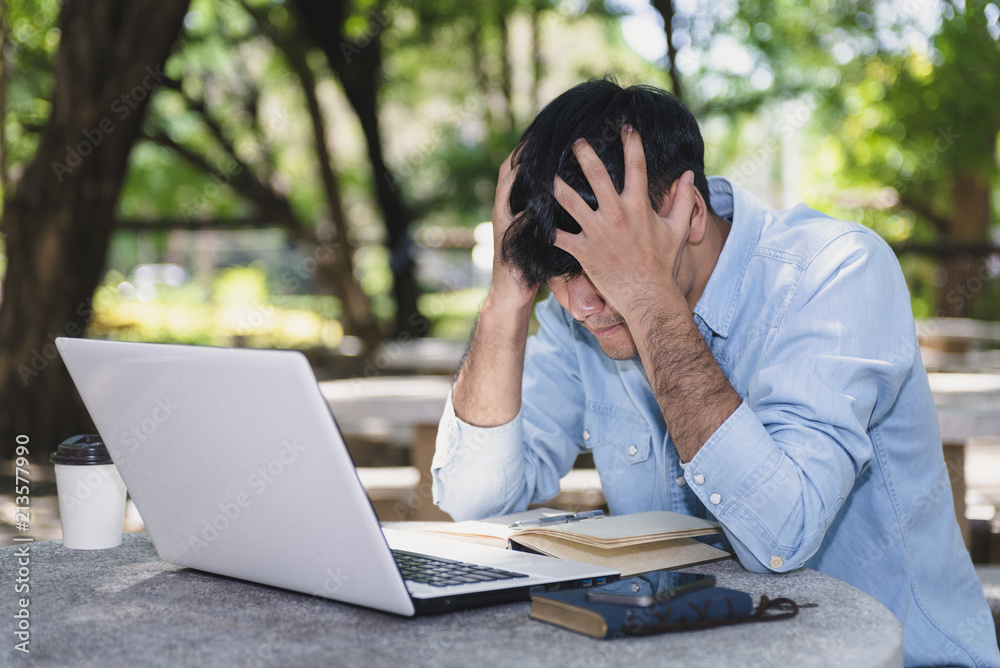 Hipster wearing blue shirt sitting city park bench is feel strain or tired with him work in park. Hipster wearing blue shirt sitting city park bench is feel strain or tired with him work in park.
