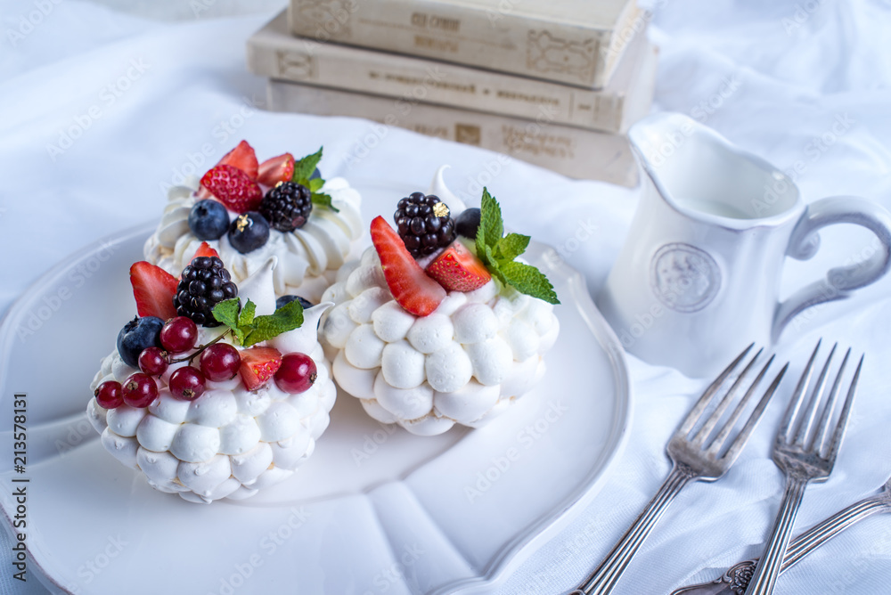 Delicate white meringues with fresh berries on the plate. Dessert Pavlova. Wedding cake.