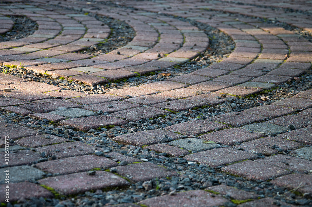 Paved labyrinth shaped square fragment outdoors in summer in warm sun setting light Paved labyrinth shaped square fragment outdoors in summer in warm sun setting light
