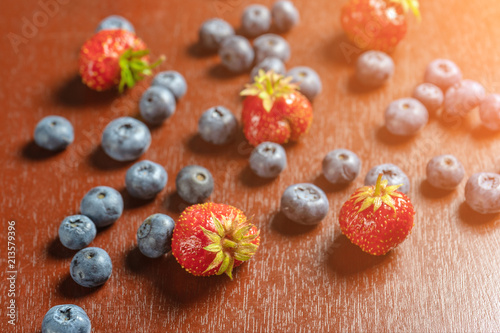 Strawberries and blueberries on a wooden table. Toned glow