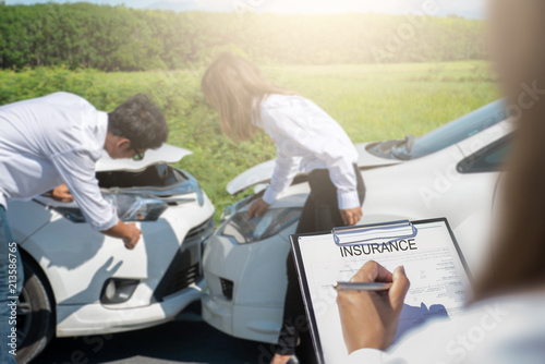 Insurance agent writing on clipboard after accident cars. © ibravery