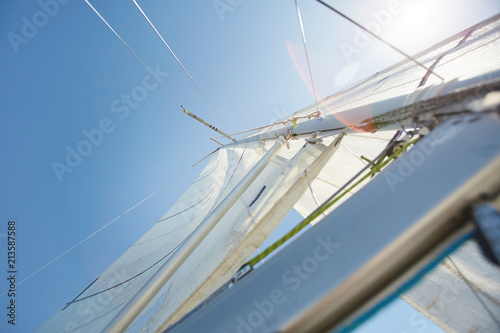 Below view of white sail with ropes used to propel boat with wind, sunlight effect