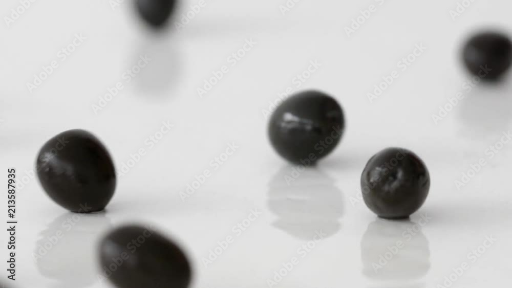 Isolated black olives roll on the table on a white background Isolated black olives roll on the table on a white background