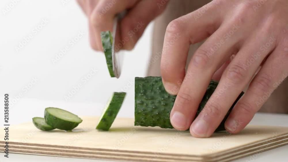 Cutting cucumbers into small slices on white background isolated Cutting cucumbers into small slices on white background isolated