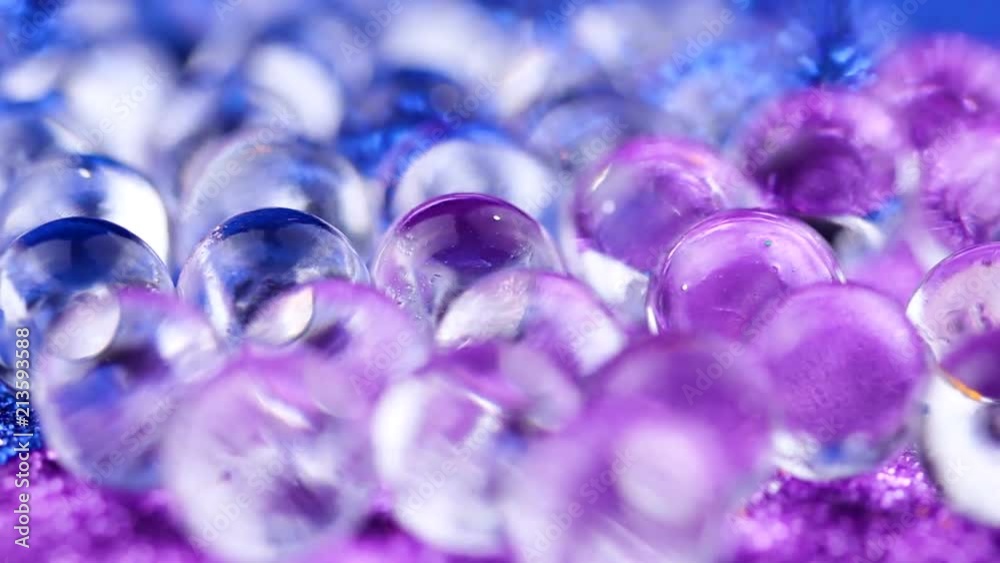 Hydrogel ball rotating on blue and purple surface. Close up macro. Hydrogel ball rotating on blue and purple surface. Close up macro.