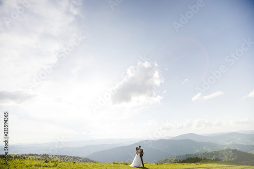 Romantic couple newlyweds posing at sunset on a background of mountains.