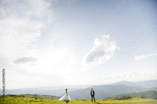 Romantic couple newlyweds posing at sunset on a background of mountains.