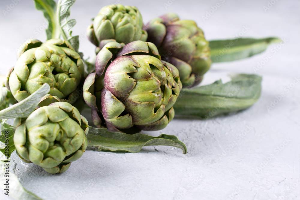 Fresh raw artichokes on grey background. Ripe organic artichoke flower with copy space Fresh raw artichokes on grey background. Ripe organic artichoke flower with copy space