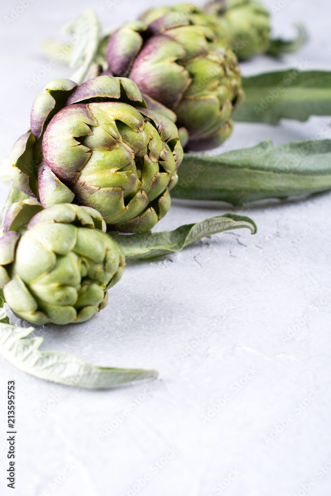 Fototapeta premium Fresh raw artichokes on grey background. Ripe organic artichoke flower with copy space