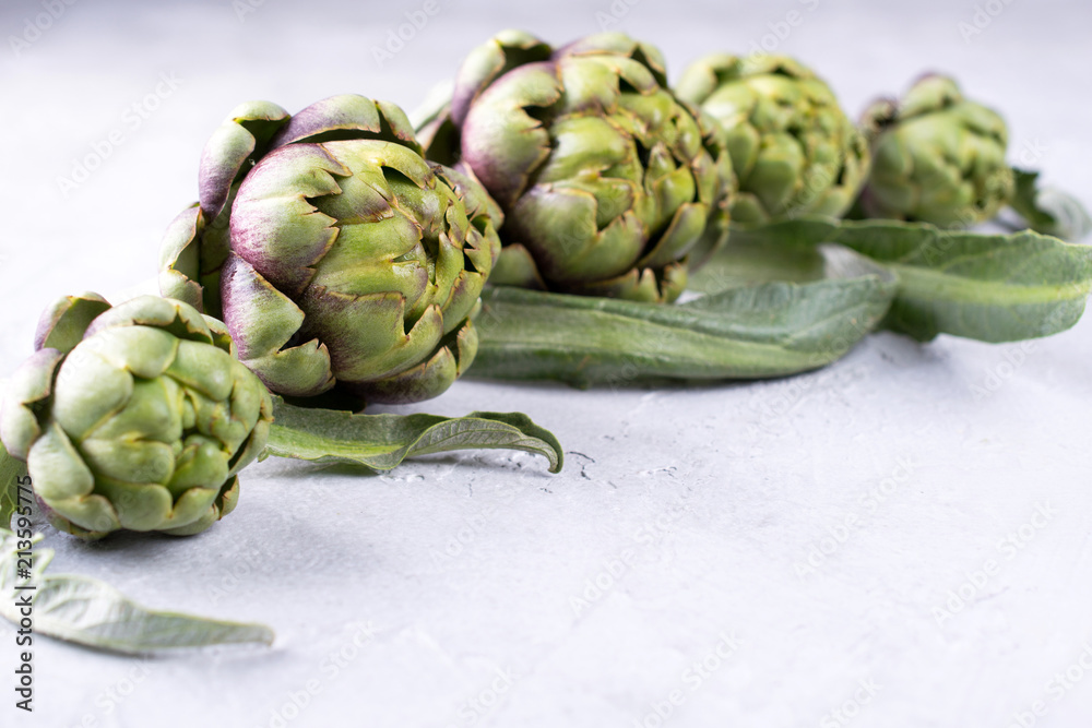 Fototapeta premium Fresh raw artichokes on grey background. Ripe organic artichoke flower with copy space