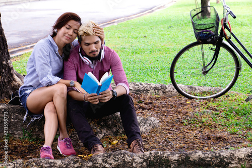 A man read a book and woman read a book too.They are in love and relax time  in public park Thailand.They are honeymoon day. 