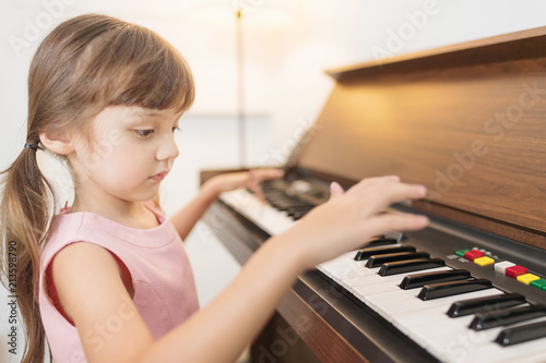 Adorable girl playing piano at home. Setup studio shooting.