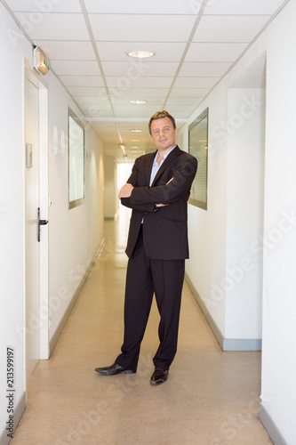 full handsome businessman on office building with arms crossed