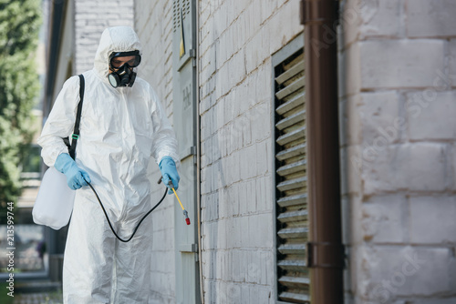 Φωτογραφία pest control worker spraying pesticides with sprayer on building wall on street