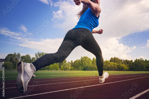 young fitness woman runner running on stadium track. The time of the jump in flight. Athletics. The concept of a healthy lifestyle and sports photo