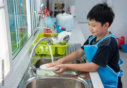 Photography Asian boy washing dishes in the kitchen