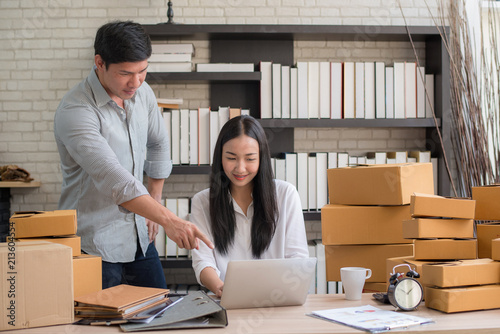 Happy young Asian man and woman at office of their business online shopping.