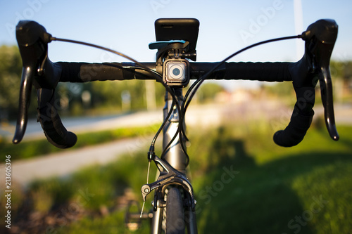 Front view of a road bike with cycling computer and sport action camera on the handlebar stem during sunset