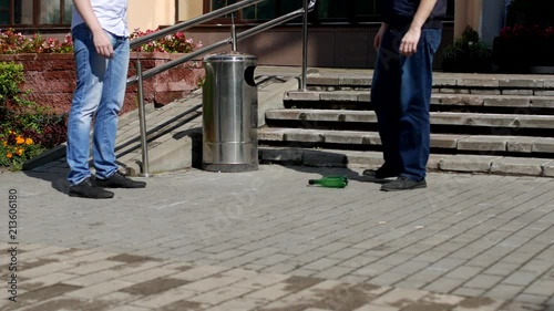 two men play football with a plastic bottle near the trash, close-up, pollution of the city with garbage photo