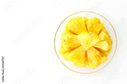 Pineapple slice on a plate placed on a wooden table.
