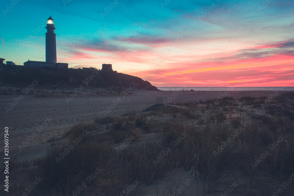 Colorful sky at magic sunset at Trafalgar lighthouse in Zahora beach, Cadiz. Summer holidays, travel vacation concepts