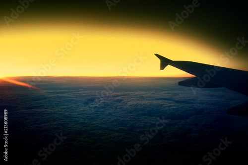 Passenger airplane. View from airplane window on the wing during sunset over the clouds. Business trip. Travel concept.