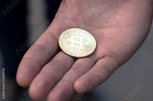 The man stretches a bitcoin, bitcoin in the hand, open palm with bitcoin
