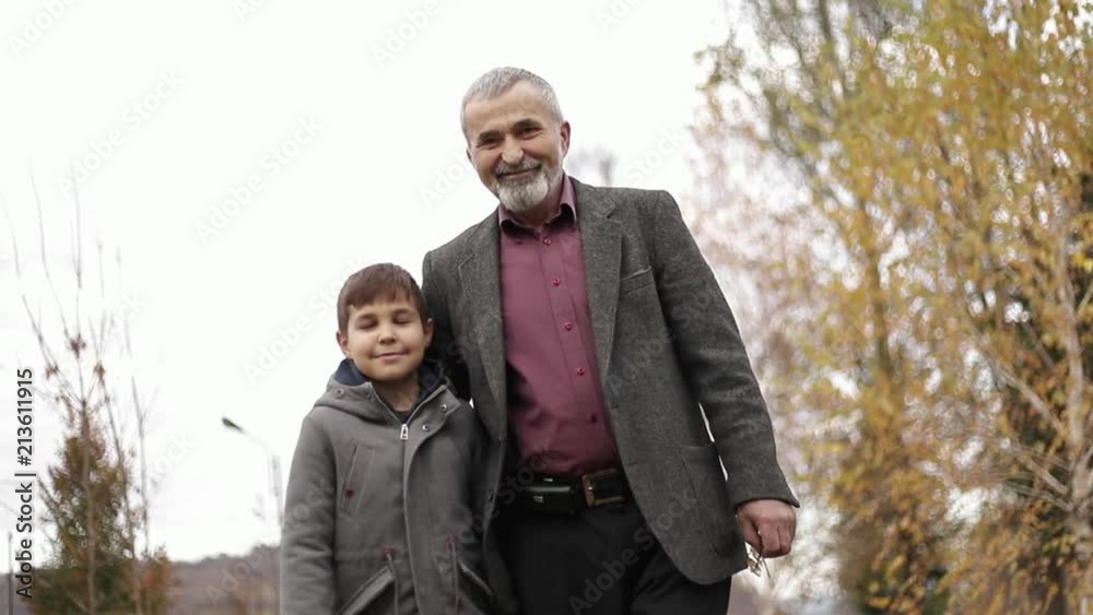 Grandpa and his grandson spend time together in the park. They are Walking in the park and rejoicing Grandpa and his grandson spend time together in the park. They are Walking in the park and rejoicing