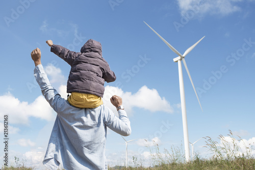 happy father and son playing at the Wind turbines generating electricity. Having quality family time together.