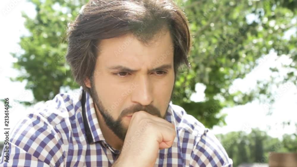 Close up of handsome man sitting outside and rubbing hands. He is worried. and touching lips with hand. Man is very sad. He is brushing head with hand. Guy is looking down and straight. He regrets. Close up of handsome man sitting outside and rubbing hands. He is worried. and touching lips with hand. Man is very sad. He is brushing head with hand. Guy is looking down and straight. He regrets.