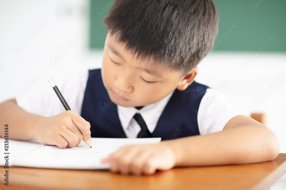 little boy writing homework in classroom little boy writing homework in classroom