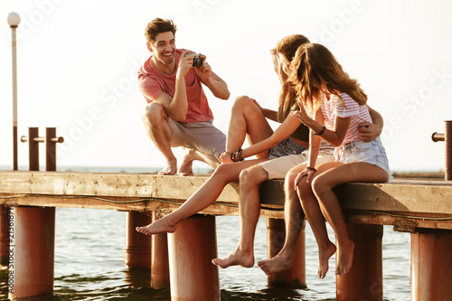 Friends sitting outdoors on the beach take a photo.