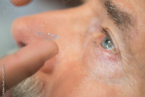 man putting contact lens in his eye
