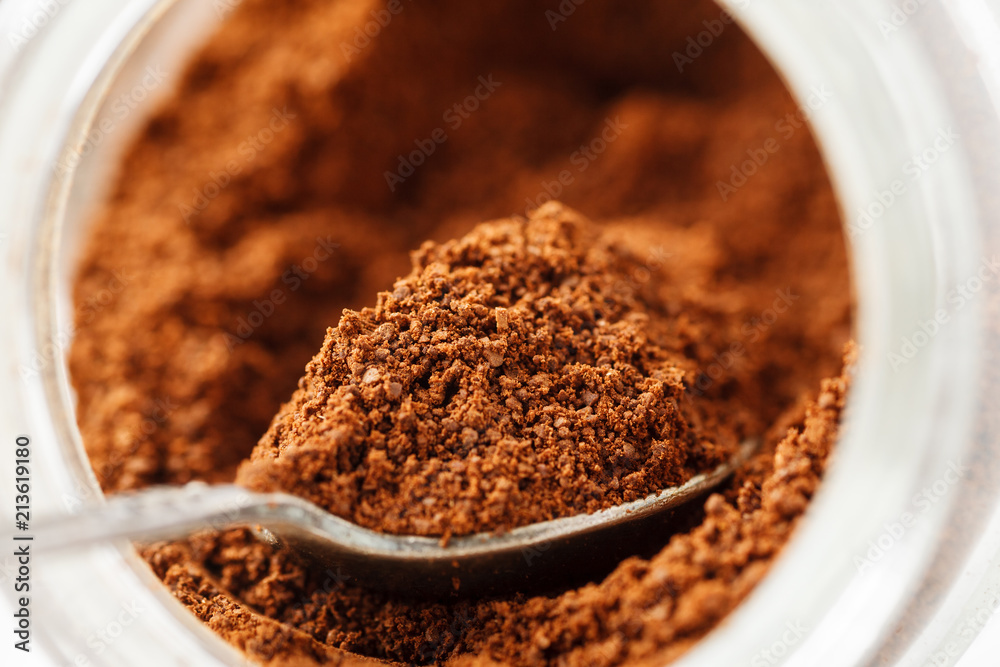 Ground natural coffee inside of glass jar with metal spoon, macro Ground natural coffee inside of glass jar with metal spoon, macro