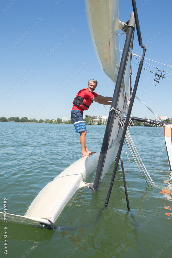 Fototapeta premium salior trying to right his catamaran after capsize