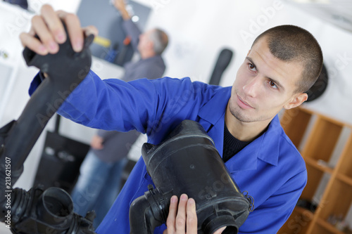 young mechanic in workshop holding parts