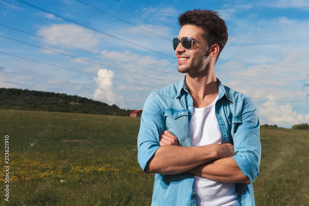 smiling confident man standing on a field looks to side