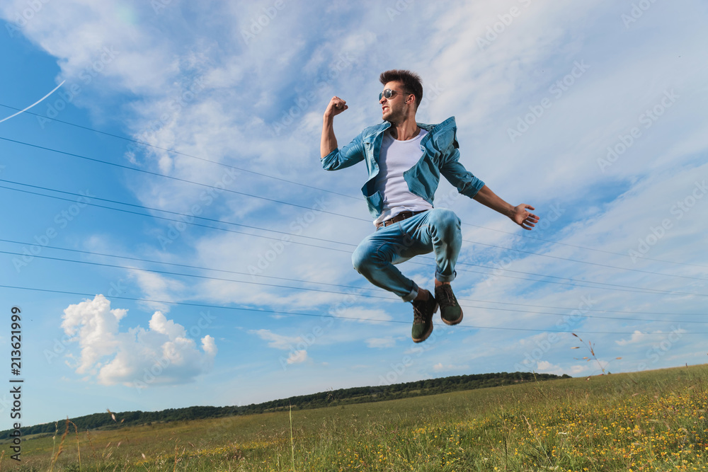 celebrating casual man jumping on a grass field celebrating casual man jumping on a grass field