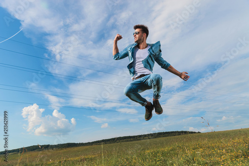 celebrating casual man jumping on a grass field