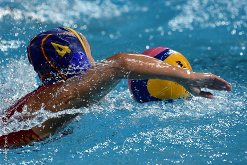 Waterpolo player swimming with ball in the pool.