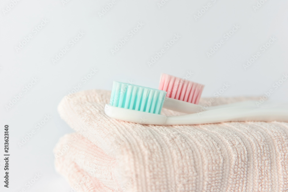Close up of plastic white toothbrush with pink bristle and toothpaste in tube on pink towel. White background, free copy space. Close up of plastic white toothbrush with pink bristle and toothpaste in tube on pink towel. White background, free copy space.