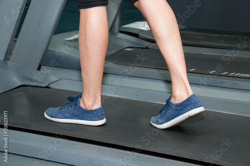 Legs in sneakers close-up. The girl is walking along the treadmill. Fitness, cardio training. The concept of weight loss