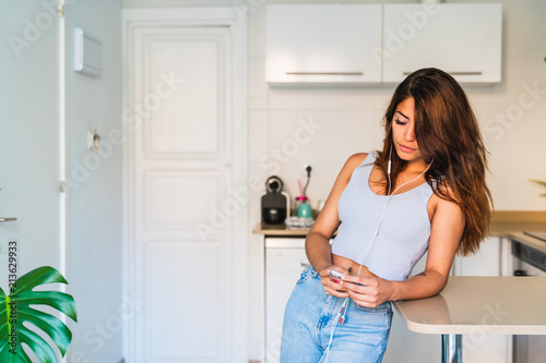 Young brunette listening to music in kitchen