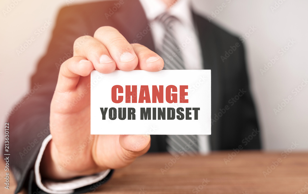Businessman holding a card with text Change Your Mindset Businessman holding a card with text Change Your Mindset