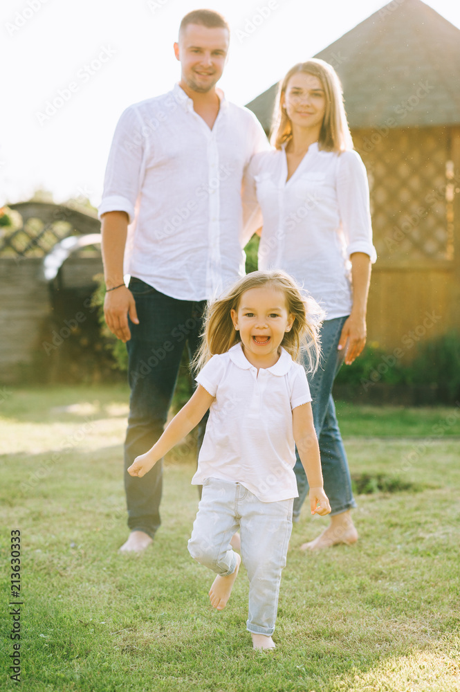 Fototapeta premium selective focus of little kid running while parents standing behind on backyard