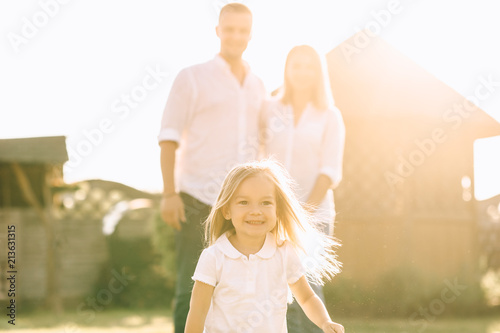 selective focus of little kid running while parents standing behind on backyard