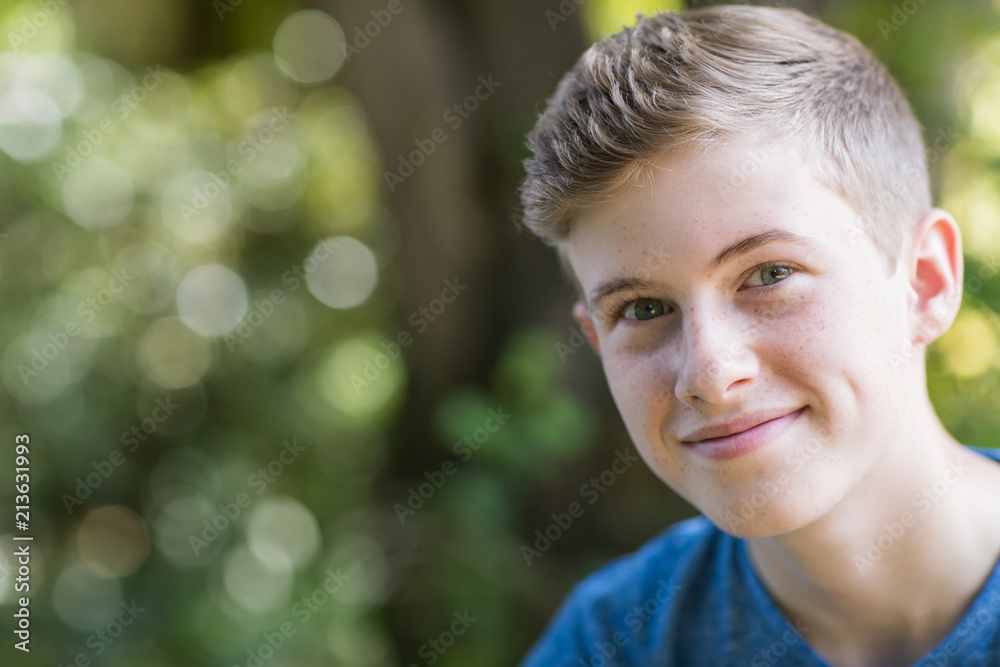Portrait Of Happy Teenage Boy Sitting Outdoors - obrazy, fototapety, plakaty 